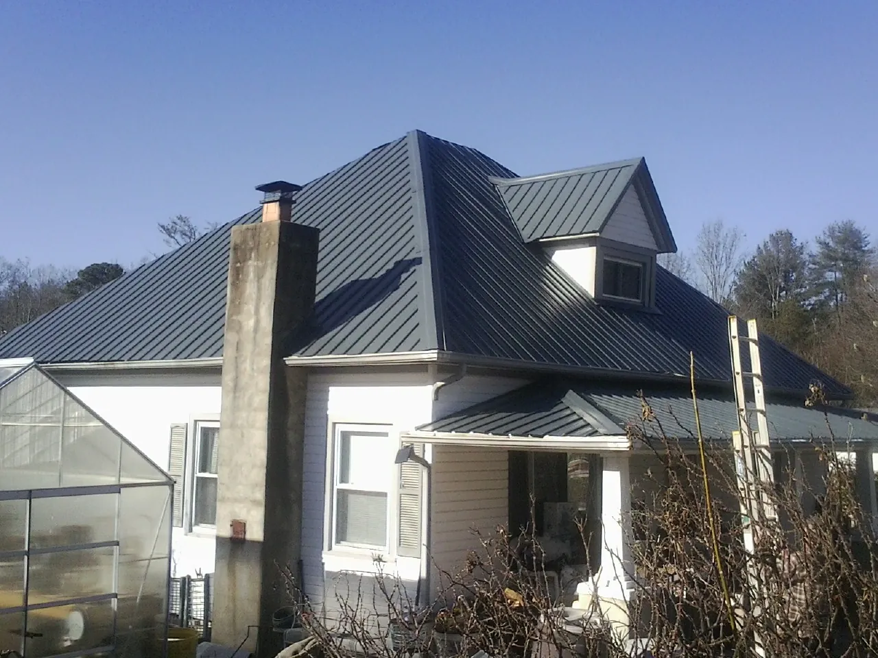 Dark blue standing seam metal roof on a white farmhouse with dormer — Slate & Tile Roof Repair by Roofing Brothers in Wood River