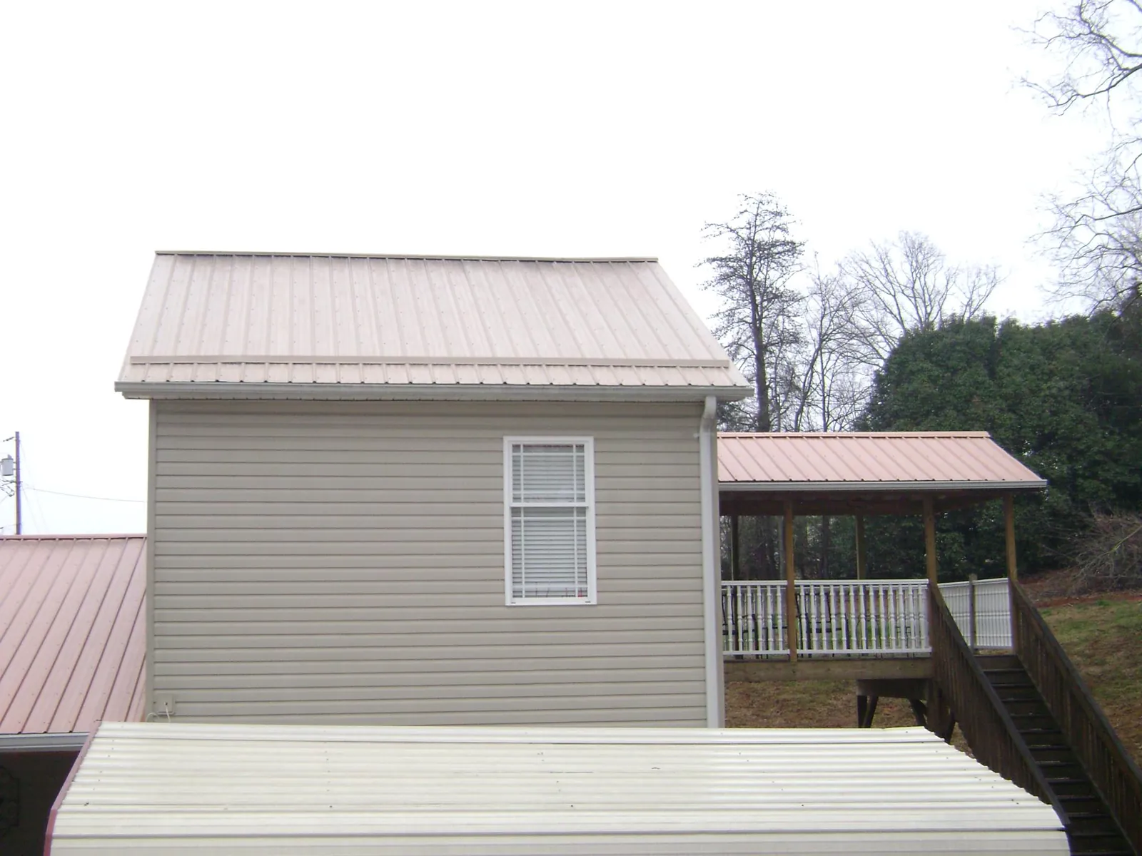 Tan metal roofs on a two story addition and attached porch, from a Roof Replacement job in Wood River