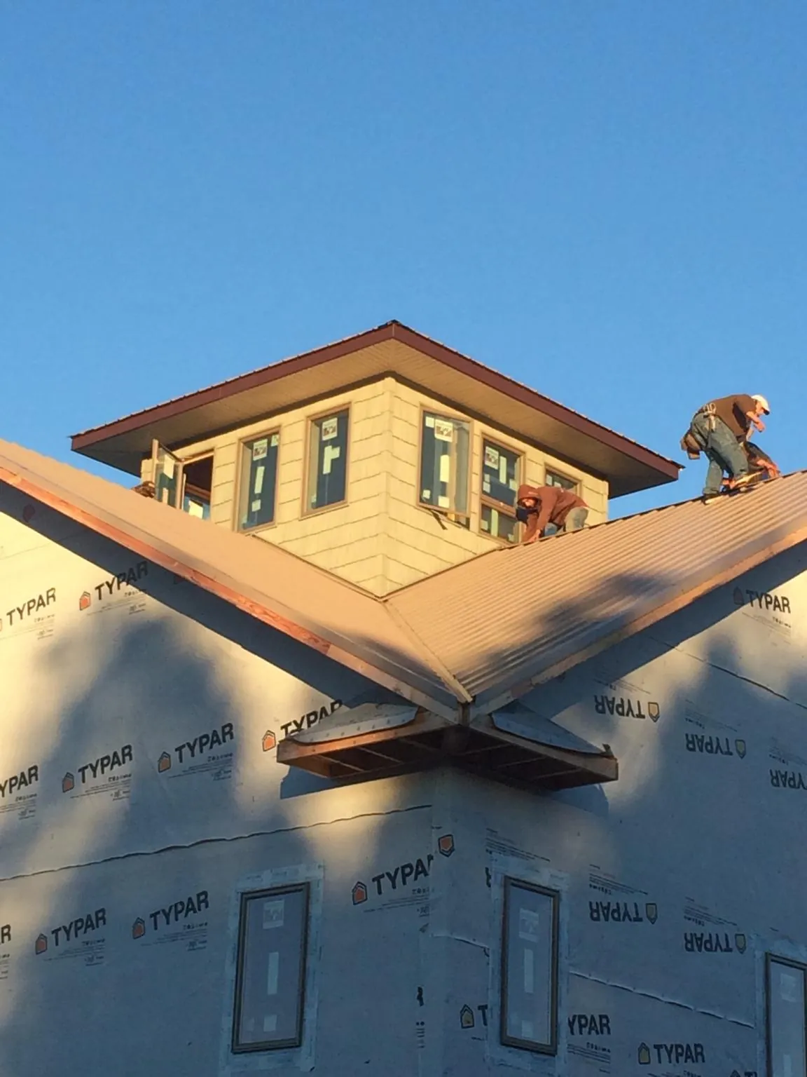 Roofers working around a rooftop cupola on a new metal roof at sunset — Roof Waterproofing in Wood River by Roofing Brothers